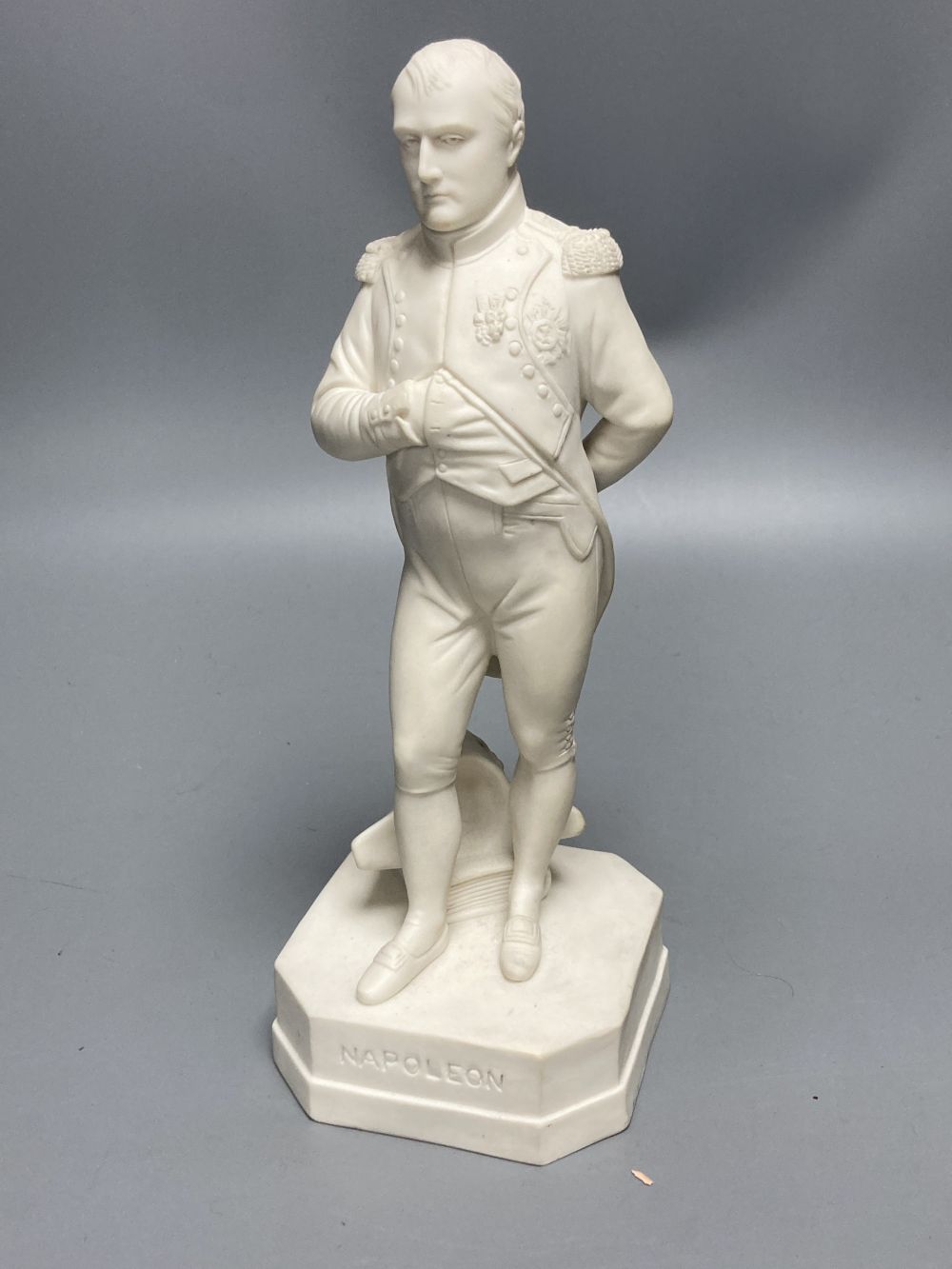 A Robinson & Leadbeater parian figure of Napoleon, standing on shaped square base, 25cm